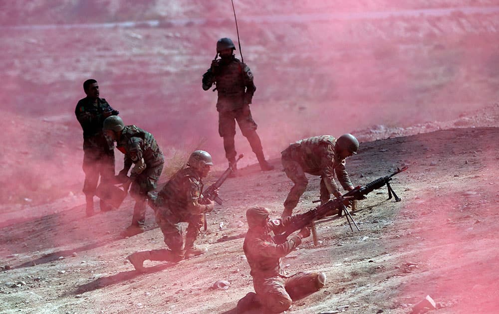 Afghan National Army soldiers make a mock attack on an enemys stronghold under smoke from colored flares during a military training exercise at Kabul Military Training Center, in Kabul.