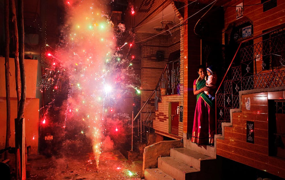 An Indian woman holds her child and watches a firecracker light up during Diwali, the festival of lights, in New Delhi.