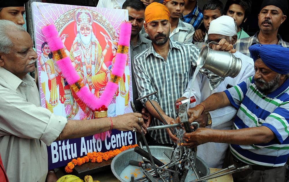 Mechanics wash their tools with milk on the occasion of Vishwakarma Puja in Amritsar.