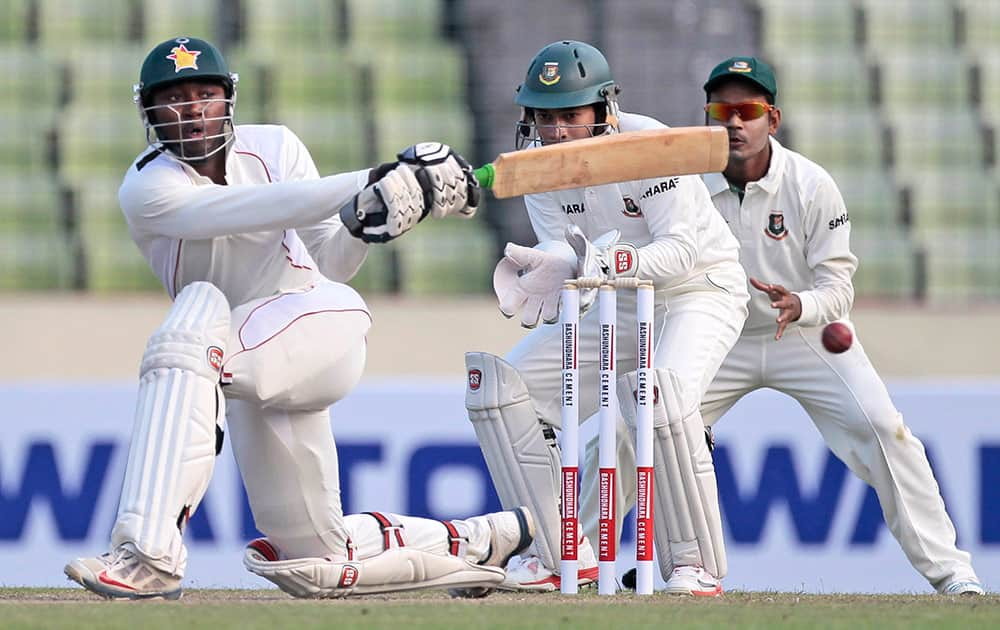 Zimbabwean cricketer Tinashe Panyangara, bats watched by Bangladesh’s captain Mushfiqur Rahim and Shamsur Rahman during the first day of the first cricket test match in Dhaka, Bangladesh.