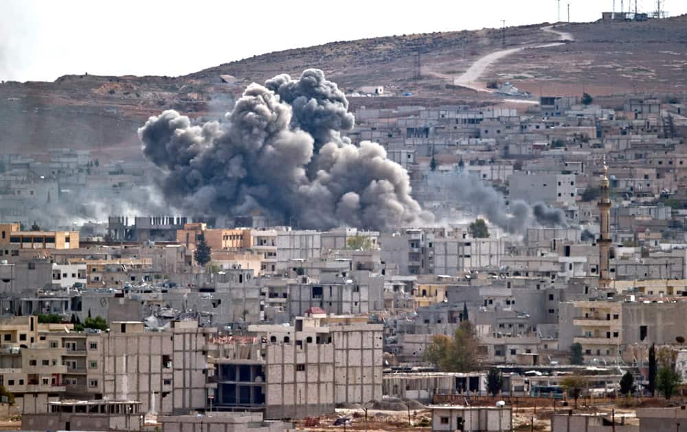 Smoke rises above the Syrian town of Kobani after an airstrike by the US led coalition, seen from a hilltop on the outskirts of Suruc, Turkey, near the Turkey-Syria border.