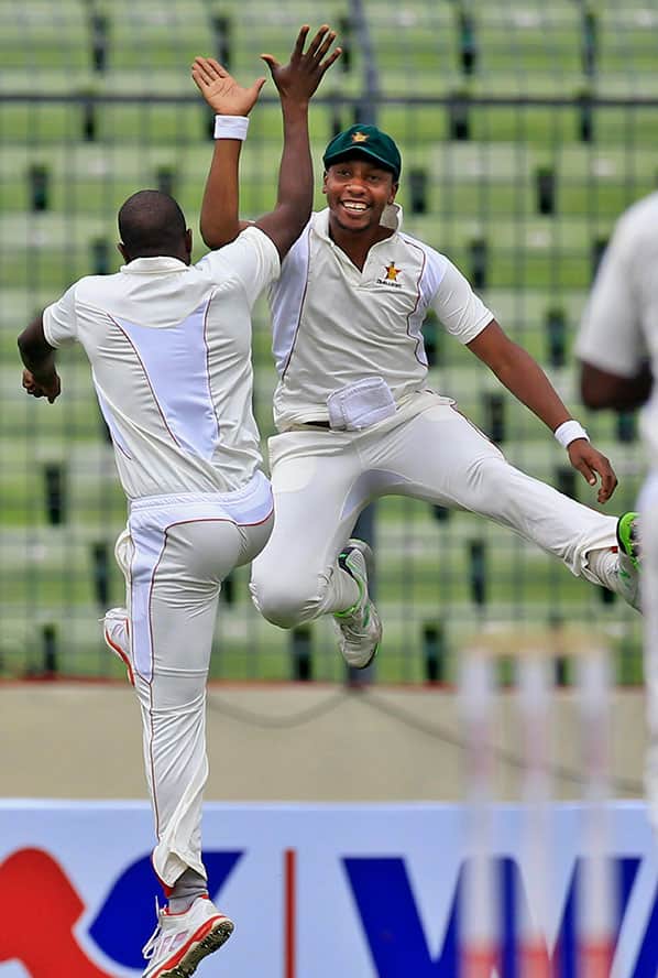 Zimbabwe's Elton Chigumbura, left, and Tinashe Panyangara jump in the air as they celebrate the dismissal of Bangladesh’s Tamim Iqbal during the third day of the first cricket test match between them in Dhaka, Bangladesh.