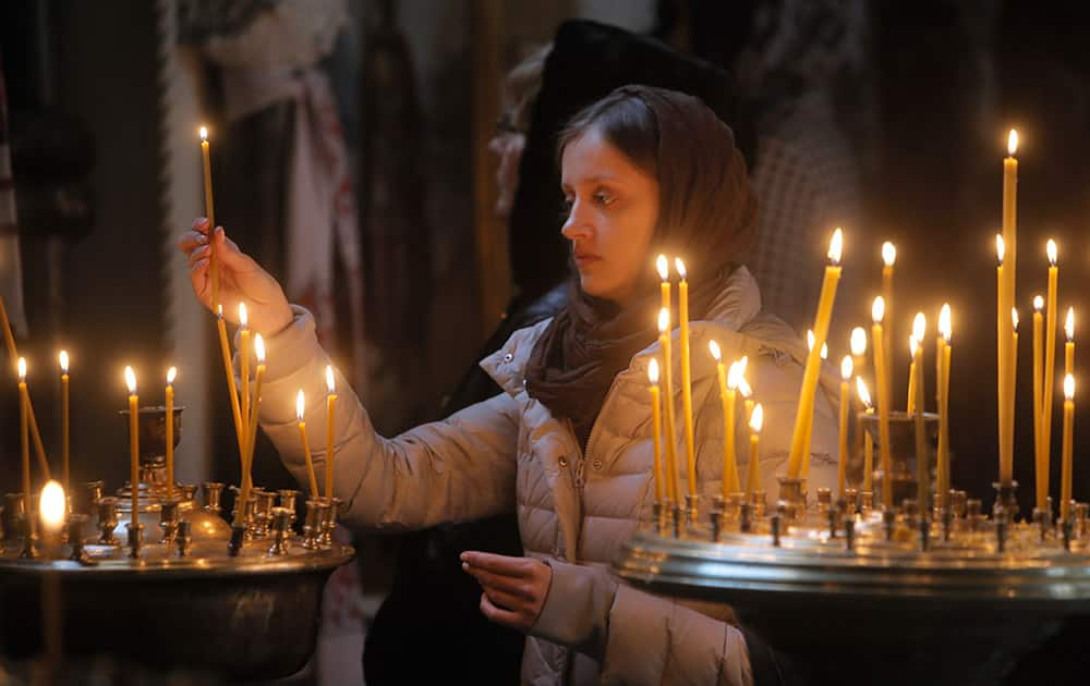 A woman lights candles at the St. Volodymyr Cathedral in Kiev, Ukraine. With more than one-third of the votes counted, two allied pro-European parties in Ukraine that ran on a platform to enact tough reforms took a joint lead Monday in a parliamentary election.