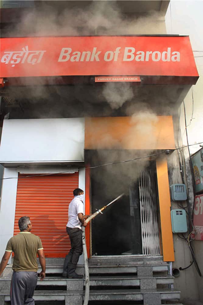 A man trying to douse the fire at a local bank in Farrukhnagar.