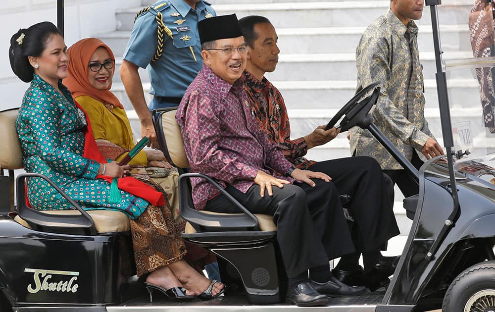 Indonesian President Joko Widodo, seated right, drives a golf cart with Vice President Jusuf Kalla, second right, Widodo's wife, Iriana, left, and Kalla's wife, Mufidaha, upon arrival for a photo session with newly appointed Cabinet members at the presidential palace in Jakarta, Indonesia.