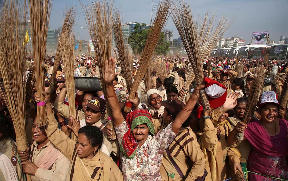 Volunteers of the sect, Dera Saccha Sauda, raise brooms as they arrive for a cleanliness drive at a public ground in Mumbai.