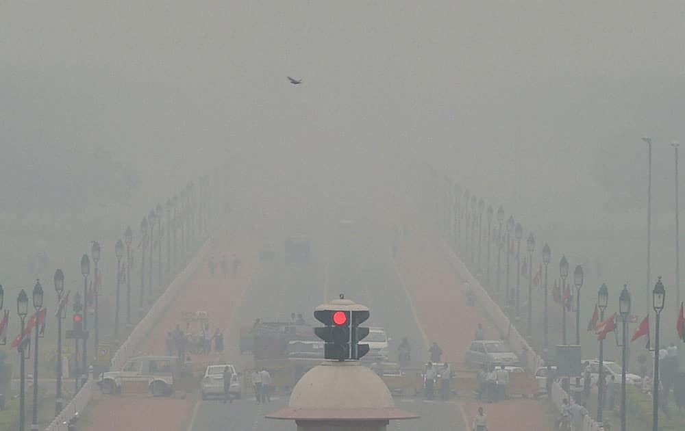 Vehicles ply at Rajpath as fog covers it in New Delhi.