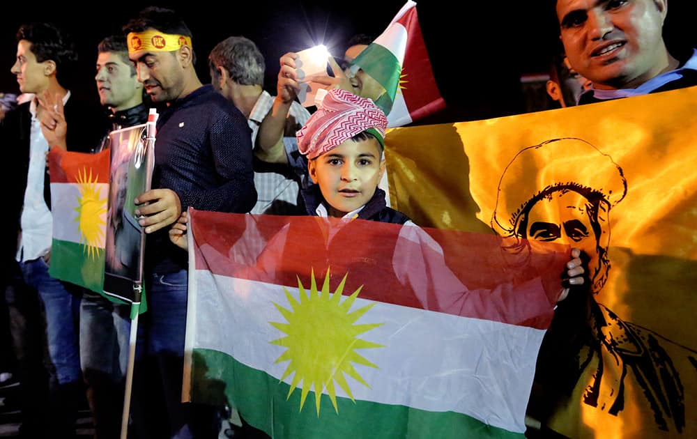 Supporters of Kurdish Peshmerga forces hold a Kurdish flags as they wait for the troops to cross the border into Turkey en route to Kobani, at the Ibrahim Khalil border crossing in the Northern Kurdish Region of Iraq.