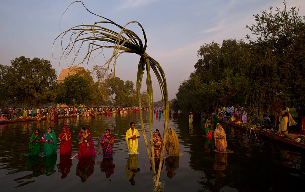 Sugarcane stalks, used for rituals, is planted into a water body as Hindu women perform rituals at sunset to mark Chhath Puja festival in New Delhi.