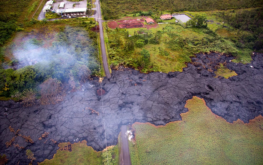 This photo provided by the U.S. Geological Survey shows an aerial view of the lava flow over Cemetery Road and Apa?a Street near the town of Pahoa on the Big Island of Hawaii. Rain fell Wednesday on a red-hot river of lava as it threatened to consume its first home on its slow advance into a rural Hawaii town.