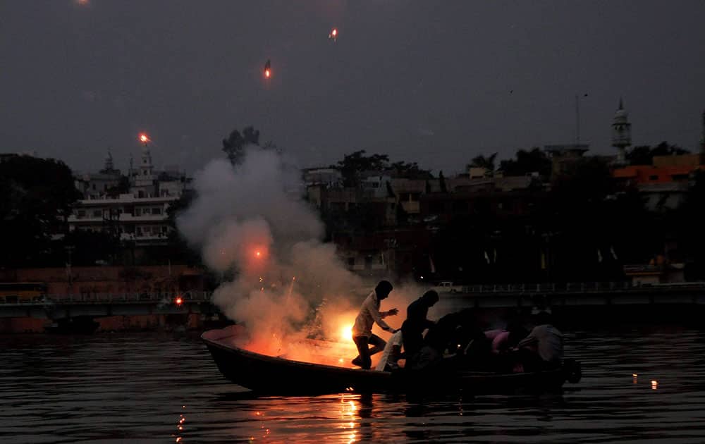 Devotees trying to save themselves while bursting crackers on their boat during Chhath puja celebration, in Bhopal.
