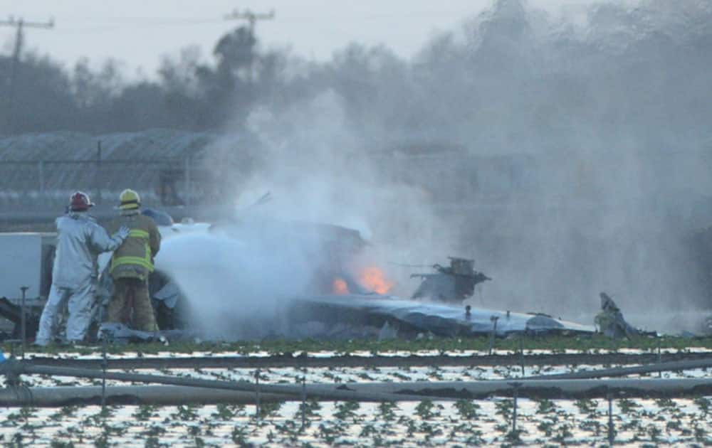 Firefighters extinguish the remaining flames of a military airplane that crashed in a field near Naval Station Ventura County near Port Hueneme, Calif., killing the pilot.