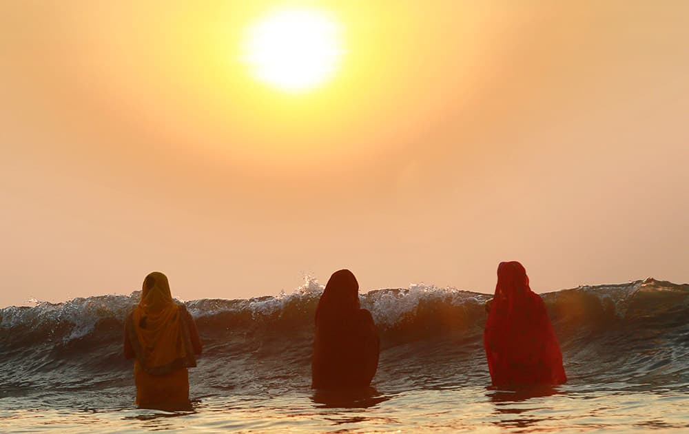 Hindu women offer prayers as the sun sets over the Arabian Sea during Chhath Puja festival in Mumbai.