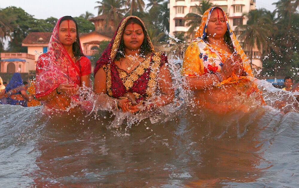 Water from waves splash on Hindu women offering prayers as the sun sets over the Arabian Sea during Chhath Puja festival in Mumbai.