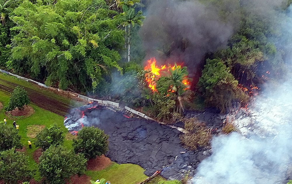 This photo provided by Pete Stachowicz of Paradise Helicopters, a house burns to the ground as lava flows around it near the town of Pahoa on the Big Island of Hawaii.