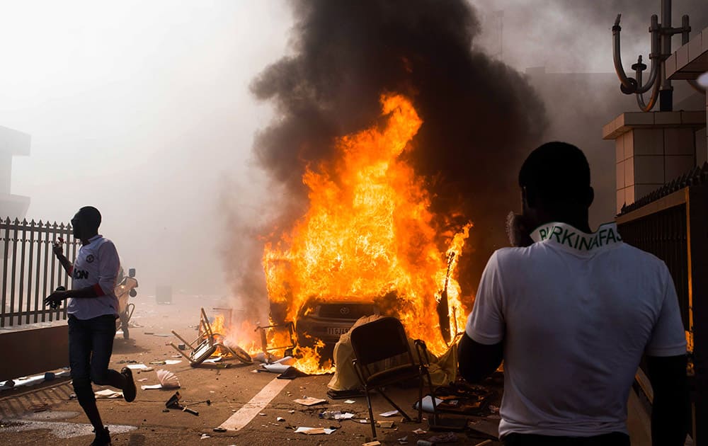 A car burns after being set alight by protesters outside the parliament building in Burkina Faso as people protest against their longtime President Blaise Compaore who seeks another term, in Ouagadougou, Burkina Faso.