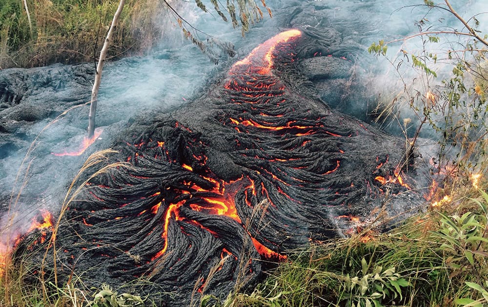 This photo provided by the US Geological Survey shows lava flow burning vegetation near the town of Pahoa on the Big Island of Hawaii.