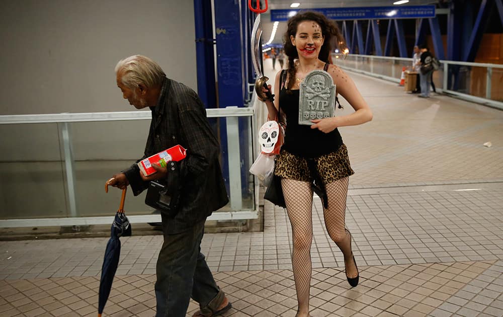 A girl dressed in a Halloween costume, runs past an elderly man during a Halloween festival in Hong Kong.