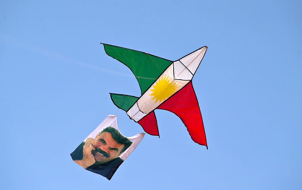 A kite in the colors of the Kurdish flag and with a photograph Abdullah Ocalan, the imprisoned leader of the Kurdistan Workers' Party (PKK), is flown above a crowd attending a rally held in solidarity with the Syrian city of Kobani in the village of Caykara, Turkey.
