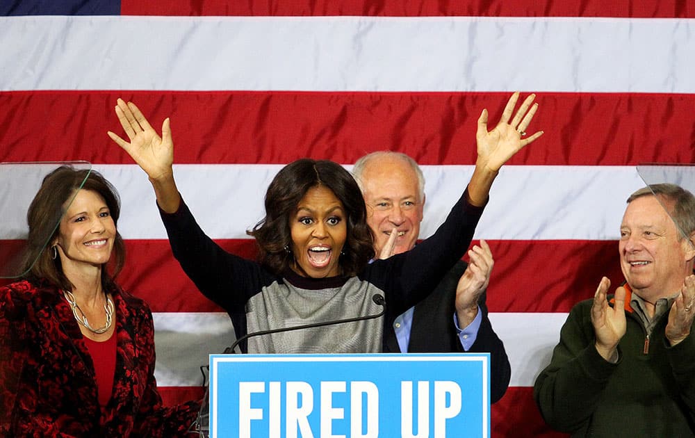 First lady Michelle Obama waves to the crowd as U.S Rep. Cheri Bustos, Illinois Gov. Pat Quinn and U.S. Senator Dick Durbin cheer from behind, during a rally for the three incumbents at Wharton Field House in Moline, Ill. 