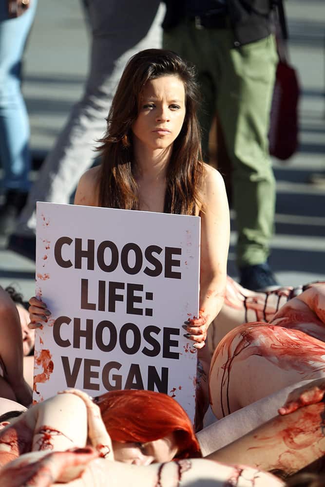A protestor holds a slogan from the People for the Ethical Treatment of Animals, PETA, as fellow demonstrators lay partially nude in London's Trafalgar Square, organised by the animal rights group, with the aim of encouraging passers-by to have compassion for animals.
