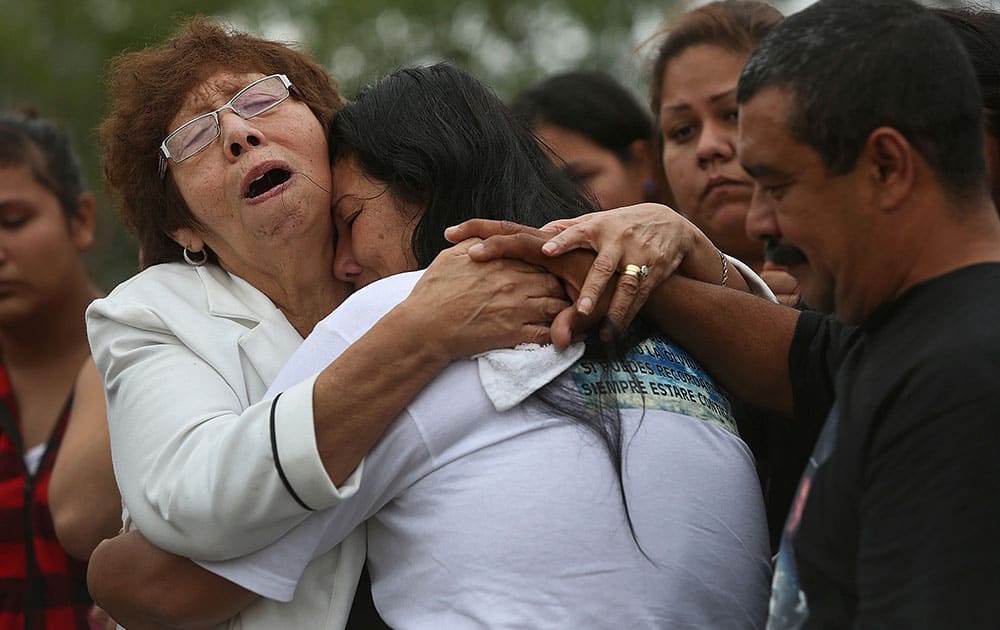 Esperanza Rivera, left, grieves with her daughter, Raquel Alvarado, for Alvarado's children, Erica Alvarado Rivera, 26, Alex Alvarado, 22, and Jose Angel Alvarado, 21, with the siblings' father, Pedro Alvarado, right, during the burial for the siblings in El Control, Mexico, where Pedro lives, on Sunday, Nov. 2, 2014.
