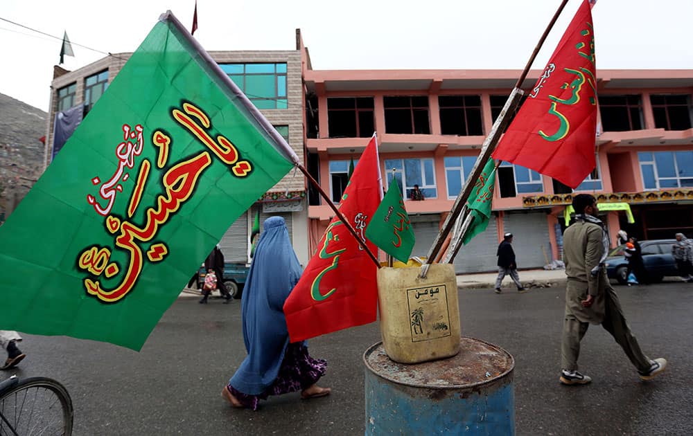 An Afghan woman walks past religious flags, ahead of the Ashoura holiday, in Kabul, Afghanistan.