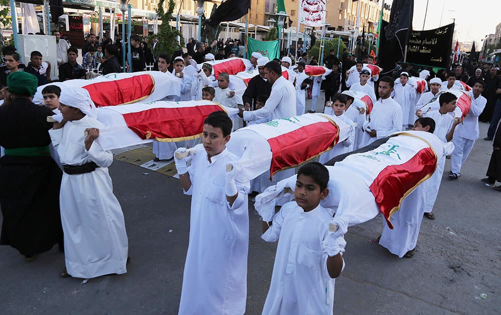 Shiite Muslim worshippers carry symbolic coffins for victims of the Islamic State group near the holy shrine of Imam Hussein ahead of the Ashoura holiday in the Shiite holy city of Karbala, 50 miles (80 kilometers) south of Baghdad, Iraq.