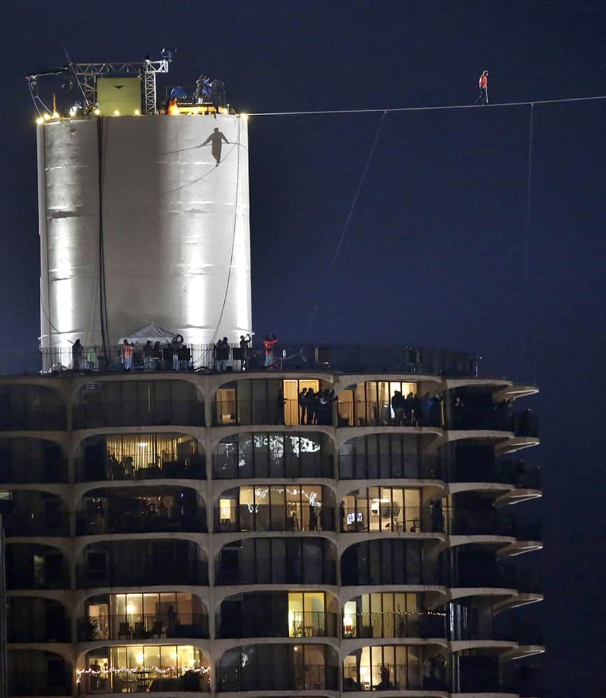 The shadow of daredevil Nik Wallenda is cast against the West Marina Tower as he begins his tightrope walk uphill at a 19-degree angle, from the Marina City west tower across the Chicago River to the top of the Leo Burnett Building in Chicago.
