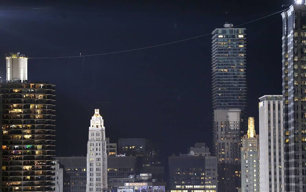 Daredevil Nik Wallenda, left center in red, makes his tightrope walk uphill at a 19-degree angle, from the Marina City west tower across the Chicago River to the top of the Leo Burnett Building in Chicago.