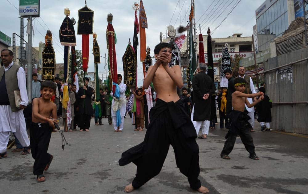 Pakistani Shiite Muslim boys flagellate themselves with knives attached to a chain, a day ahead of Ashoura holiday during the holy month of Muharram, in Peshawar, Pakistan.