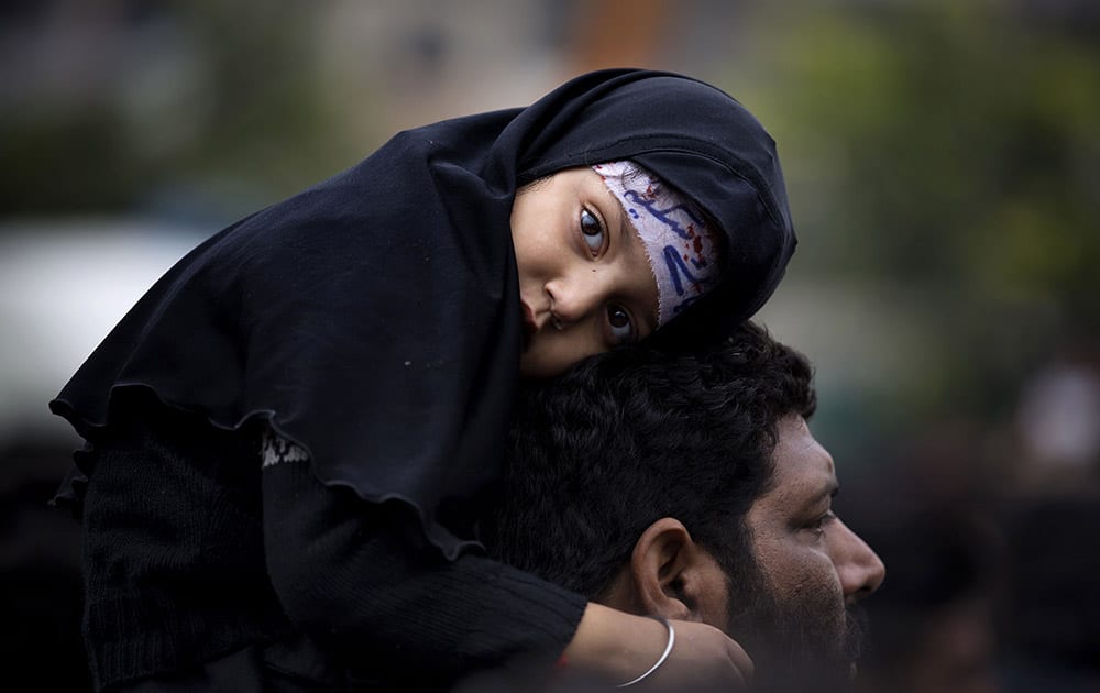 A Pakistani Shiite girl attends a mourning procession, a day ahead of Ashoura holiday during the holy month of Muharram, in Islamabad, Pakistan.
