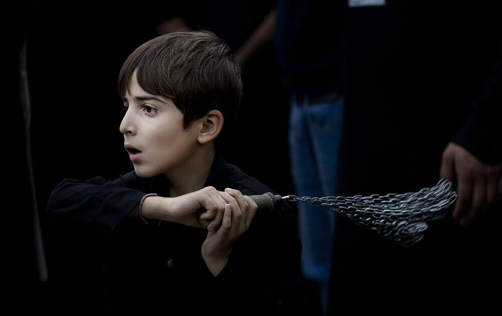 A Pakistani Shiite boy beats himself with chains during a mourning procession, a day ahead of Ashoura holiday, in Islamabad, Pakistan.