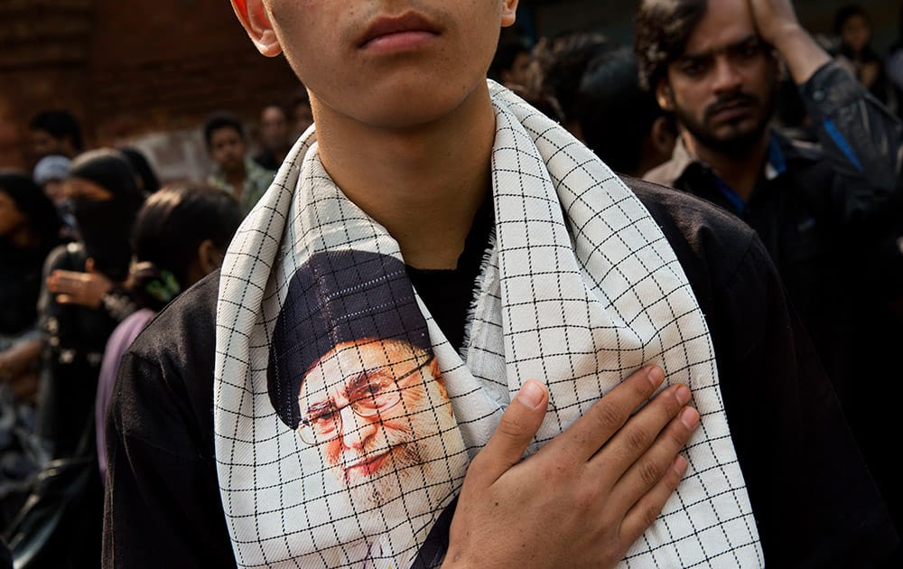 A Shiite Muslim wears a scarf with a portrait of Iranian supreme leader Ayatollah Ali Khamenei as he beats his chest during a procession to mark Ashoura in New Delhi, India.