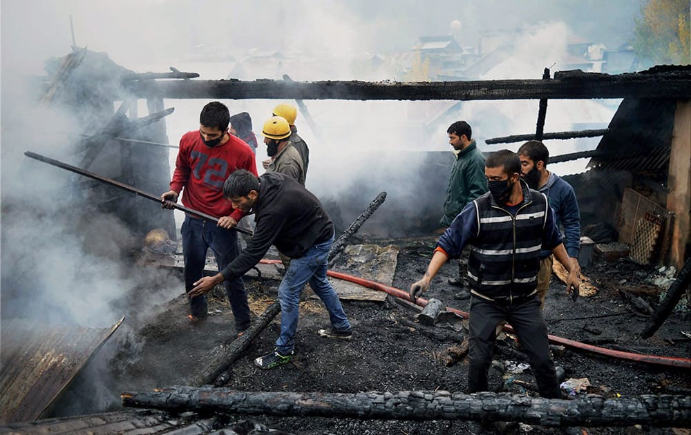 Firefighters and civilian work to extinguish a fire that broke out at Kadipora in Anantnag district.