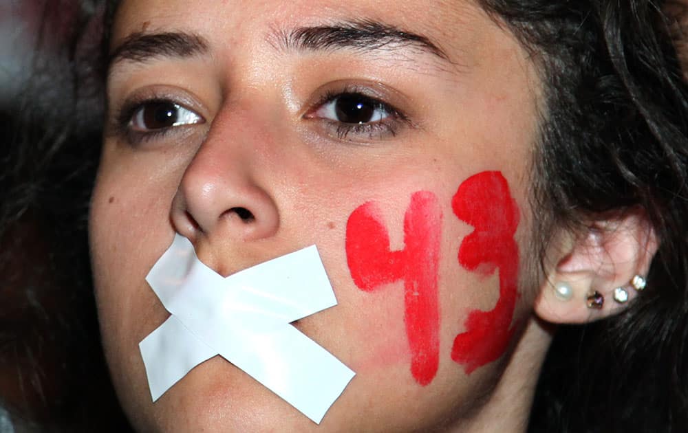 A demonstrators with her mouth taped shut and the number 43 painted on her face marches in protest for the disappearance of 43 students in the state of Guerrero, in Mexico City.