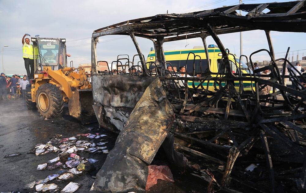 A man moves a bus destroyed in a car crash near the village of Damanhur, north of Cairo, Egypt.