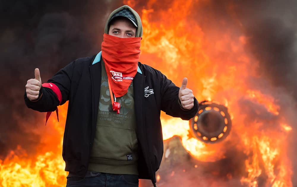 A protestor gives thumbs up as he stands in front of a burning car during a national trade union demonstration in Brussels.