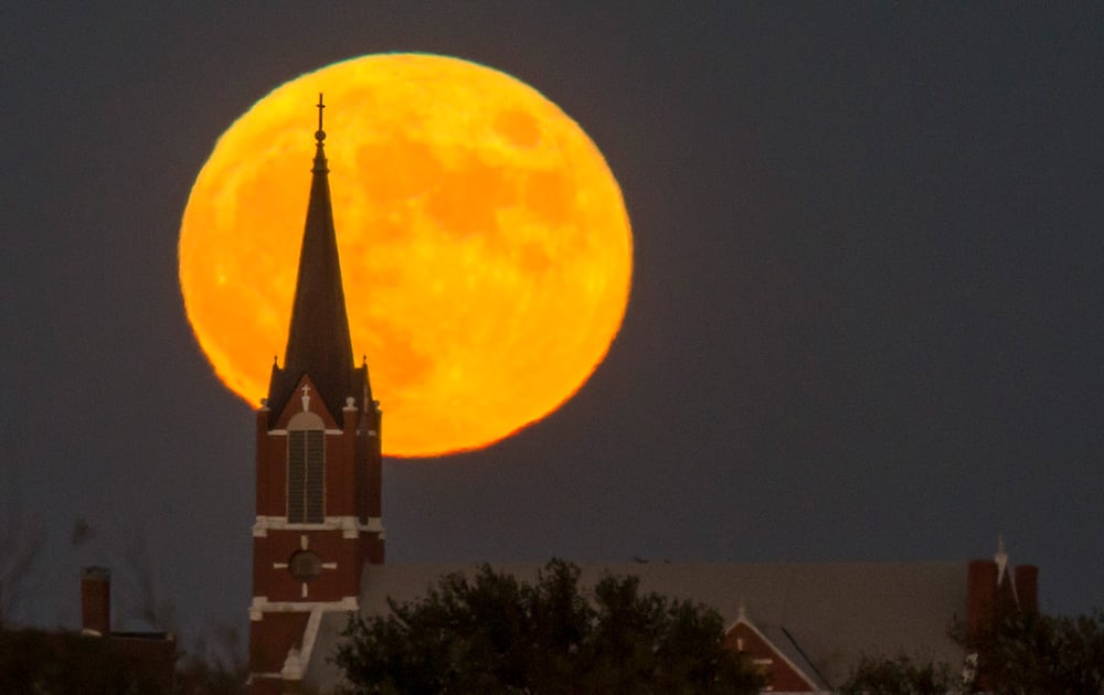 A full moon rises behind St. Joseph Ost Catholic Church in rural Reno County, Kan.