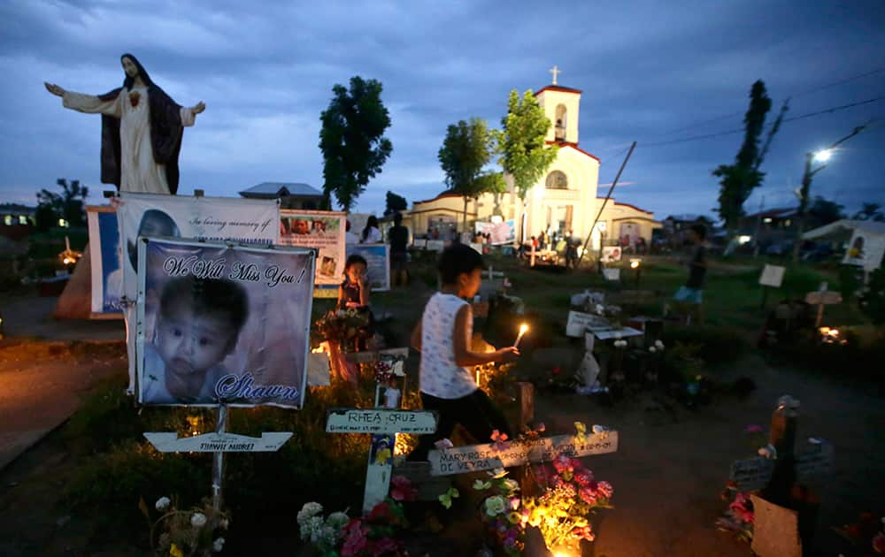 Relatives light candles at the mass grave for typhoon Haiyan victims outside San Joaquin church at Palo township, Leyte province in central Philippines.