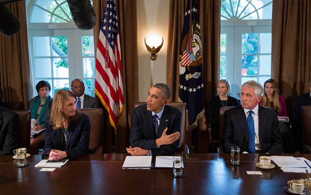 President Barack Obama, flanked by Heath and Human Services Secretary Sylvia Matthews Burwell, left, and Defense Secretary Chuck Hagel speaks to the media before a meeting with his cabinet members in the White House Cabinet Room in Washington.