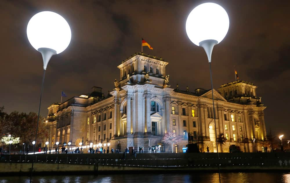 Balloons of the art project 'Lichtgrenze 2014' (lit. 'lightborder 2014') are illuminated in front of the Reichstags building in Berlin, Germany. The light installation featuring 8,000 luminous white balloons commemorates the division of Berlin where the 25th anniversary of the fall of the wall is marked with numerous events on the weekend.