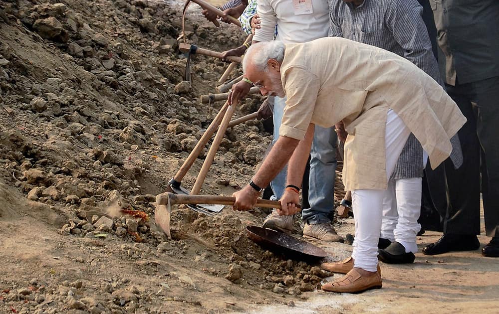 Prime Minister Narendra Modi wields a spade as he participates in the Swachh Bharat Campaign at Assi Ghat.