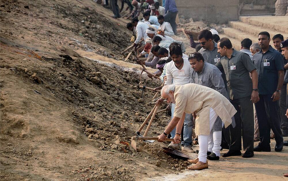 Prime Minister Narendra Modi wields a spade as he participates in the Swachh Bharat Campaign at Assi Ghat.