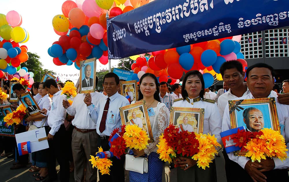 Cambodia civil servants stand holding portraits of King late Norodom Sihanuk and King Norodom Sihamoni during the Independence Day celebration at the Independence Monument in Phnom Penh, Cambodia.