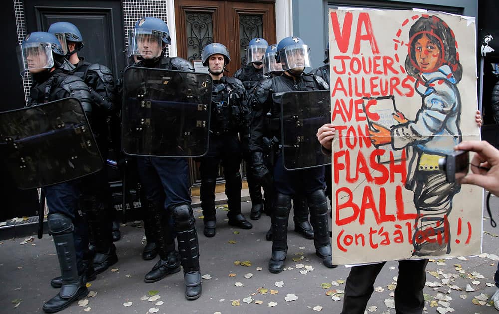 A protester holds a placard reading `Go playing away with your flashball, we keep an eye on you` during a march against police violence and in tribute to Remi Fraisse, a 21-year-old environmental activist who died during clashes between security forces and protesters of the Sivens dam project, in Paris, France.