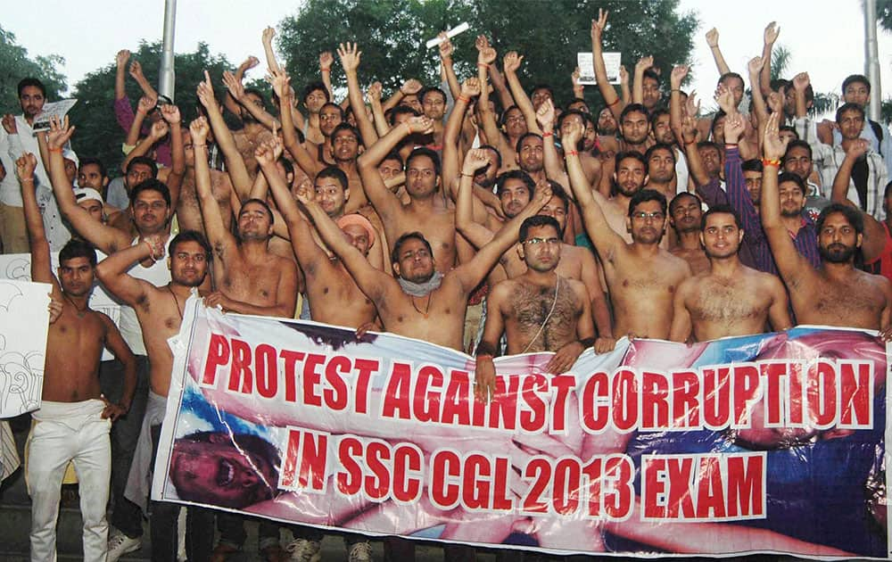 Students shout slogans and hold a poster during their protest against corruption in Combined Graduate Level Test 2013 in Allahabad.