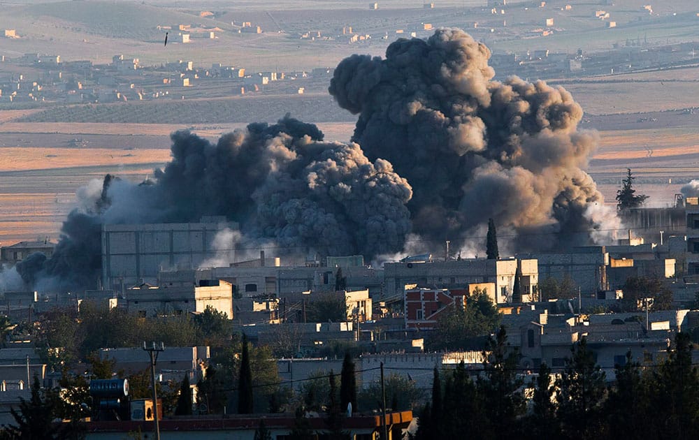 A bombs, seen top left, falls on an Islamic State position in eastern Kobani, during an airstrike by the US led coalition, seen from a hilltop outside Suruc, on the Turkey-Syria border.