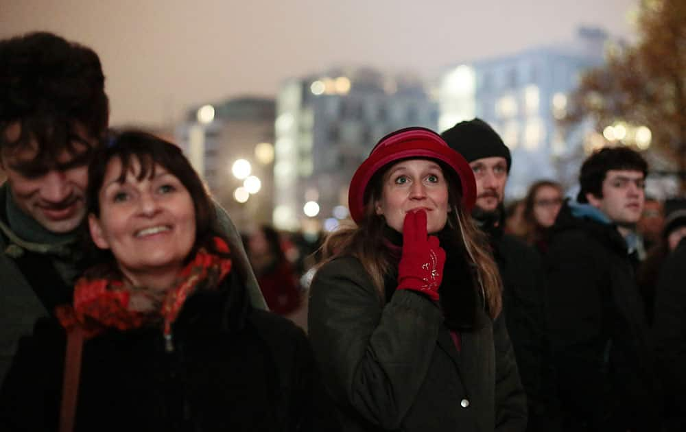 People watch to a giant screen with sequences from the fall of the wall in 1989 to commemorate the Fall of the Wall near the Reichstag Building in Berlin, Germany.