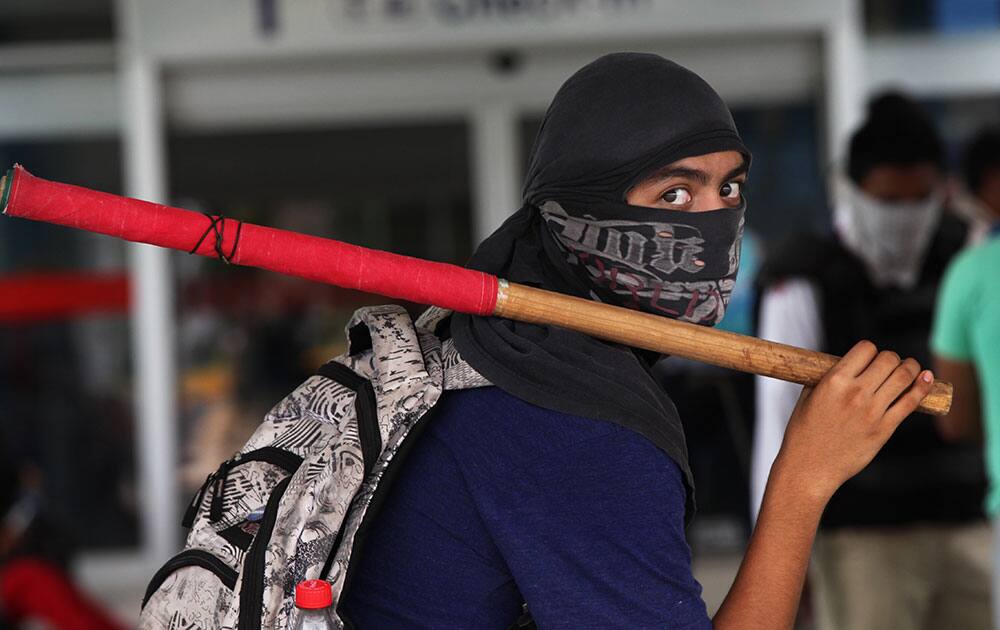 A masked student holds a stick during a protest against the disappearance, and probable murder, of 43 students in the state of Guerrero, at the Acapulco airport in Mexico.